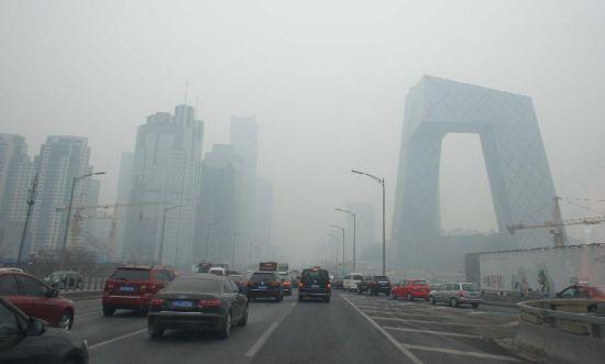 　　2月21日，車輛行駛在霧霾籠罩的北京街頭，中央電視臺(tái)新址大樓依稀可見。