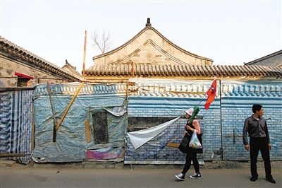 昨日，小石碑衚同，一位導(dǎo)遊帶著遊客走過建築圍擋。西城區(qū)今年計劃啟動什剎海舊城保護(hù)示範(fàn)項目。新京報記者