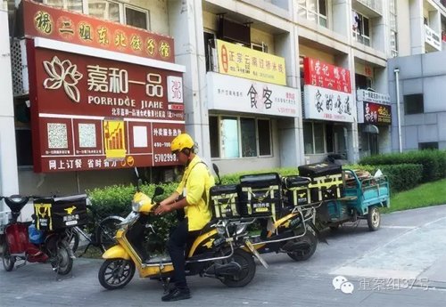 2016年7月26日，通州區(qū)北京像素小區(qū)，一棟樓的一樓開了密集的餐館，餐館外停著美團(tuán)的外賣車，一名送餐員正要騎車去送餐。