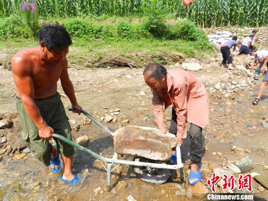 61歲老黨員杜守禮用殘臂扶住小車上的石頭?！堸i翔 攝