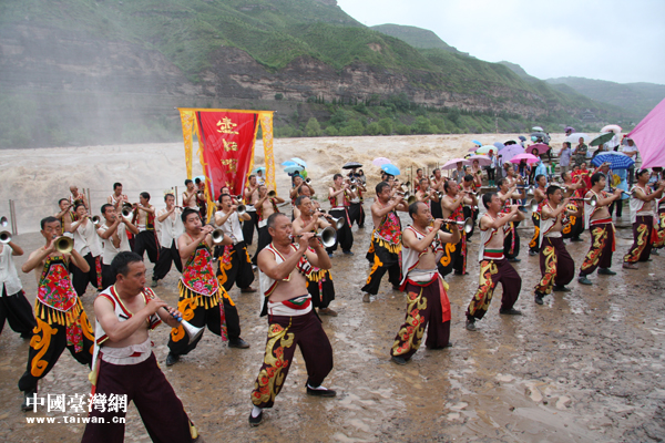 40多位當?shù)氐臐h子在瀑布前吹起了震天的嗩吶